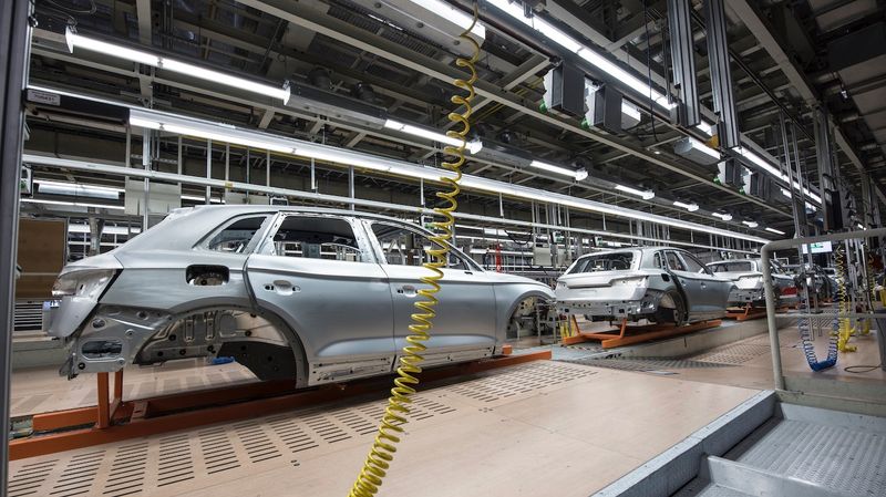 A line of partially assembled cars on a factory floor