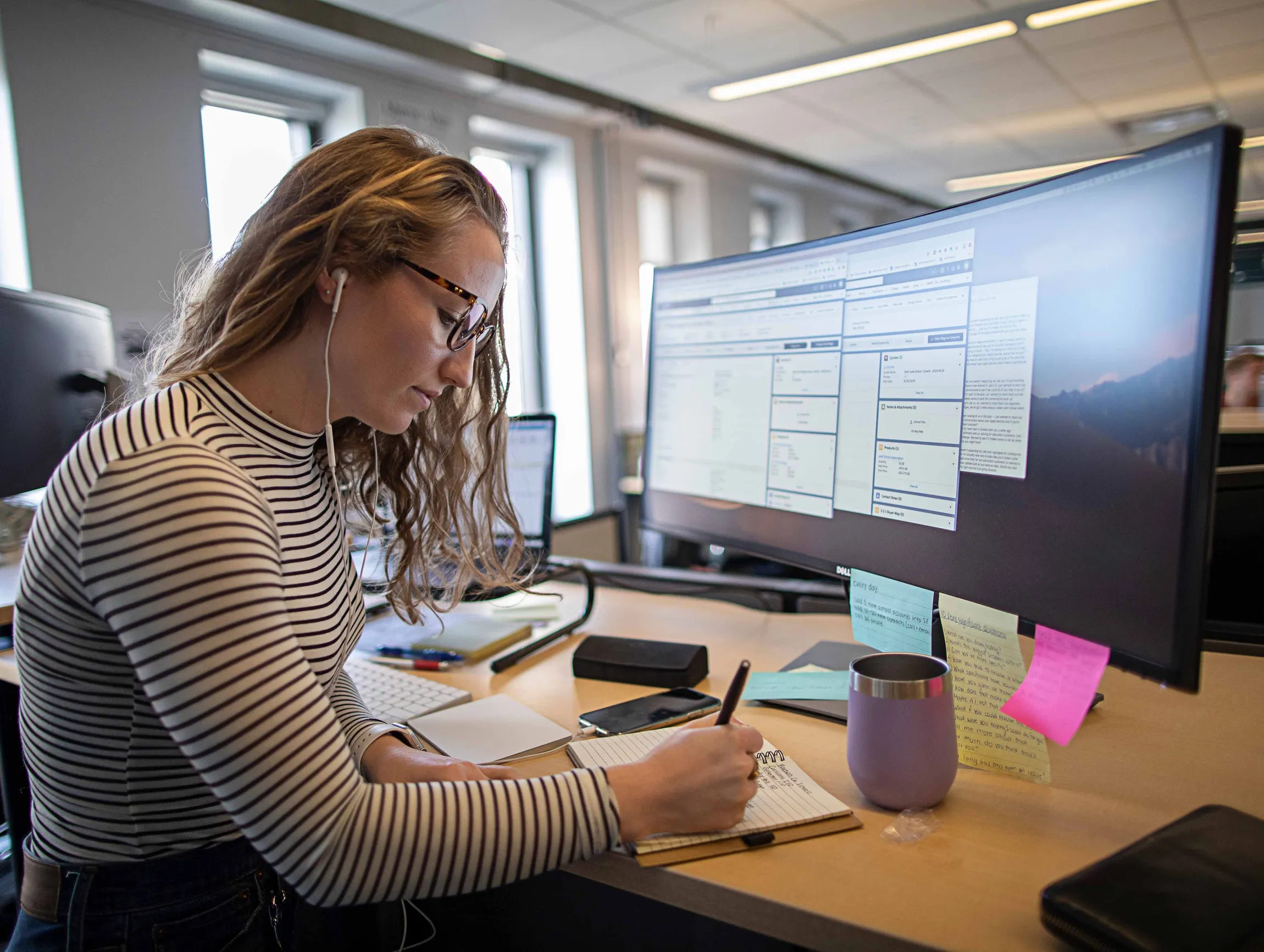 A worker takes notes in front of a large Apple screen