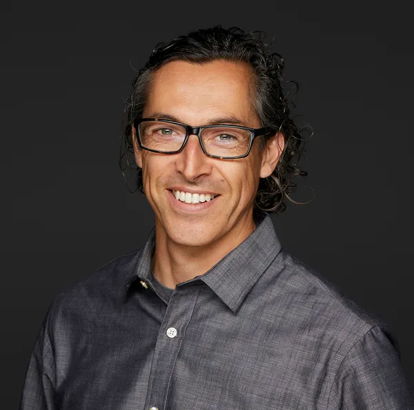 A headshot of Michael Hernandez wearing glasses and smiling