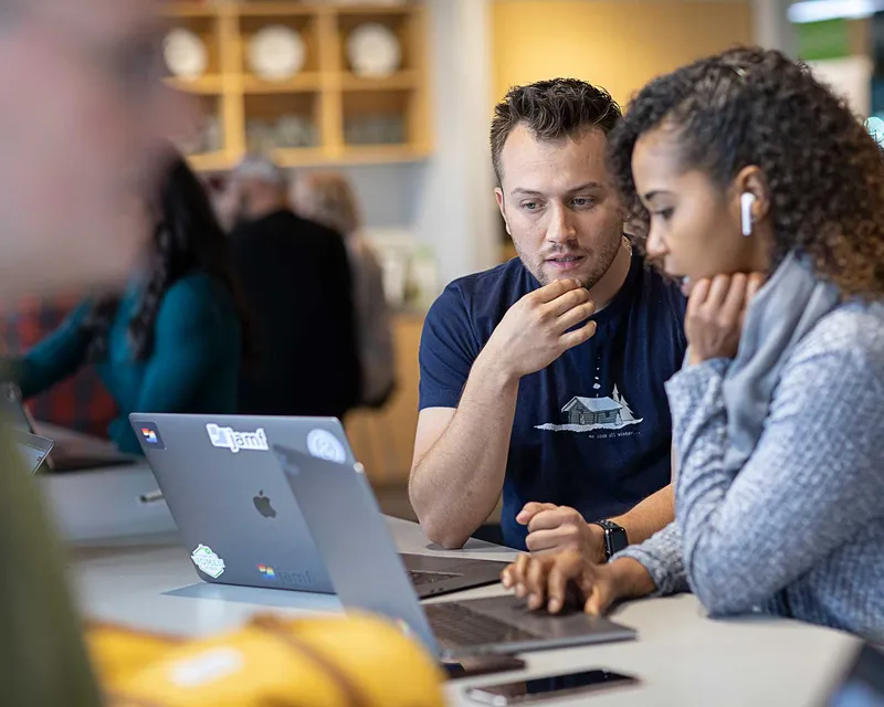 Male and female Jamf professionals collaborating over an Apple MacBook.