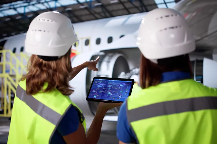 Image of an aviation crew working on an iPad with a plane in front of them.