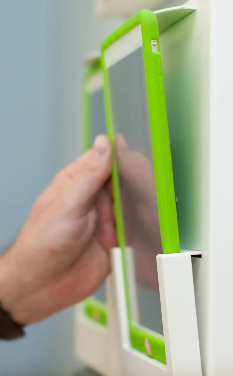 Medical staff takes an iPhone off of a rack on the wall.