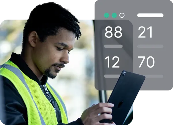 A person wearing a safety vest looks intently at a tablet displaying a dark interface with the numbers 88, 21, 12, and 70. The clean design suggests a mobile device management system, like Jamf, for monitoring or data analysis.