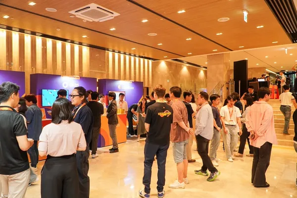 A crowd of people in an indoor event space, with a person in a black t-shirt that includes the phrase