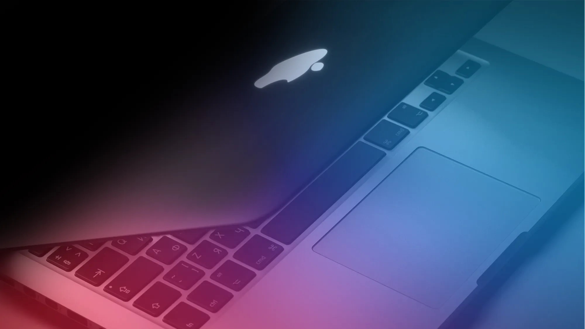 Apple MacBook Pro with display tilted open and abstract rainbow shining on the keyboard.