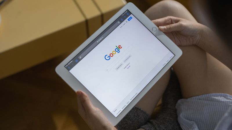 Two hands holding an iPad Mini with the browser navigated to the Google home page