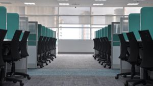 An aisle in an empty office between two rows of cubicles with dividers