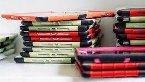 Three stacks of iPads with brightly colored cases against a white background