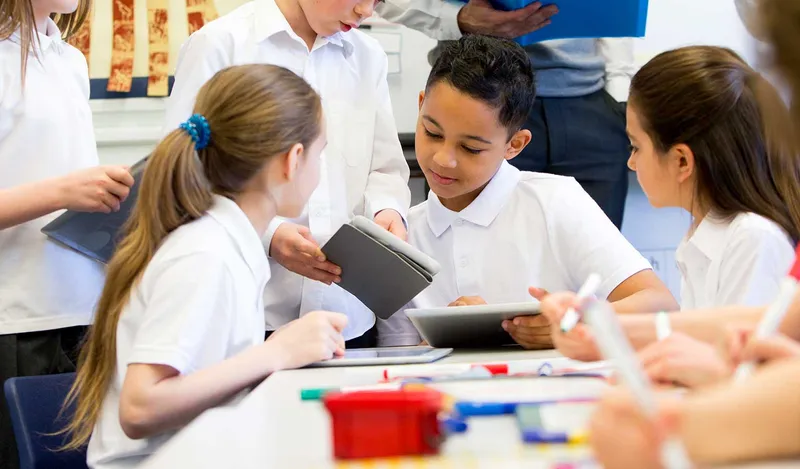 Children work together in a classroom on iPads managed by Jamf School.