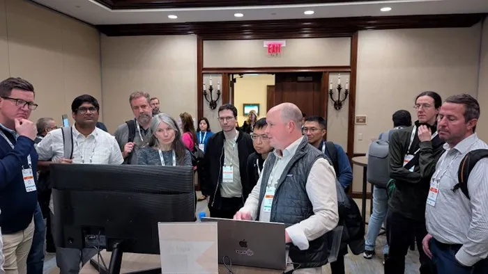 Group of people gathered around a computer watching a demo