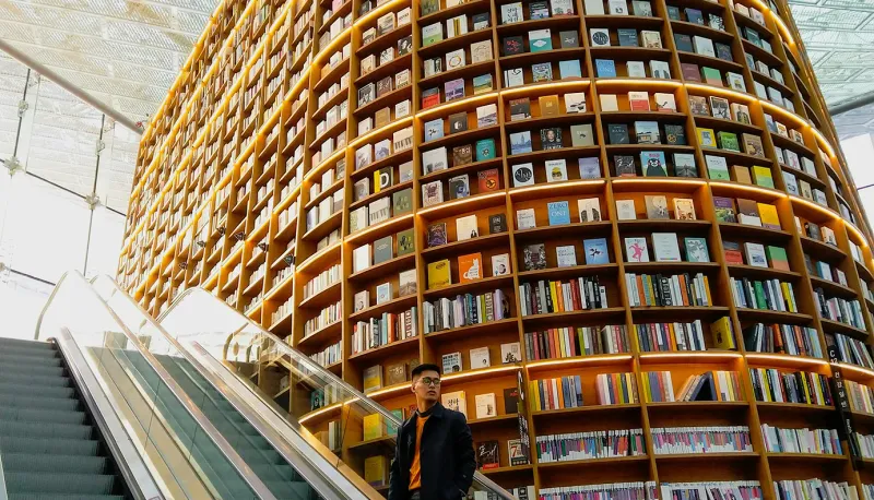 A person taking an elevator up to access the second-level bookshelf filled with information.