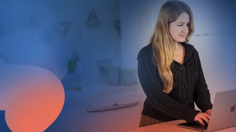 An employee with long light hair and complexion, wearking a black sweater, works on a MacBook managed by Jamf through declarative device management. The background is abstract colors.