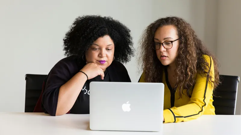Two people in an office learn about Jamf 11 on a MacBook.