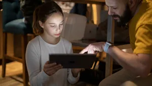 A parent helps a student with work on her Jamf School-managed iPad as they sit in the kitchen.