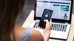 Identity threat protection with Okta and Jamf: a woman holds a locked iPhone up to her Mac screen.