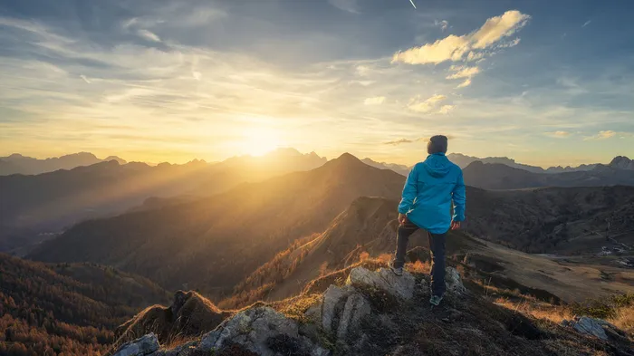 Climber overlooking the sunset from the top of a mountain.