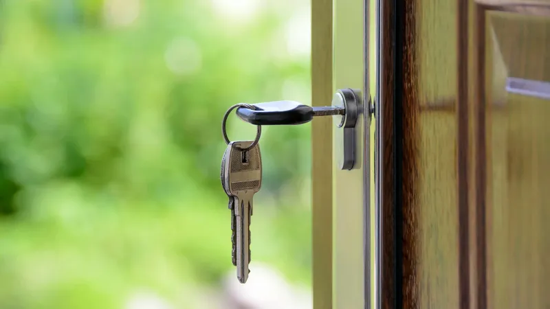A key in a wooden door's lock with a background of green lawn symbolizes continuous conditional access with Jamf and Okta
