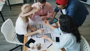 Students around a table, working on blueprints with an iPad and iPhone managed by Jamf.