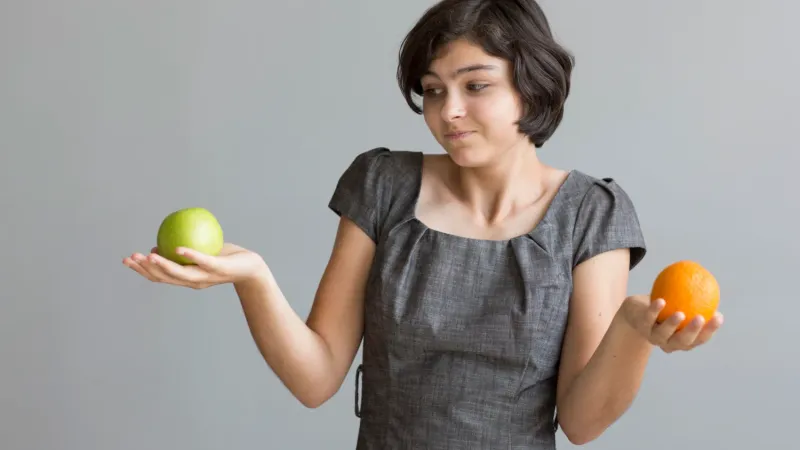 A young teacher compares an apple to an orange.
