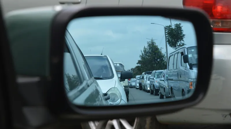 An endless row of cars viewed from a car's side mirror.