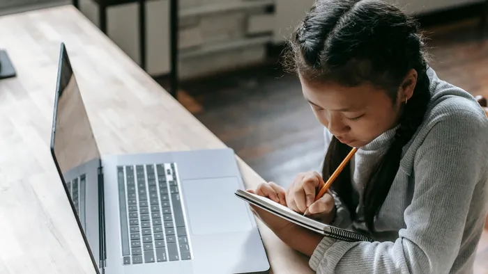 Young student taking notes from a MacBook running macOS 26