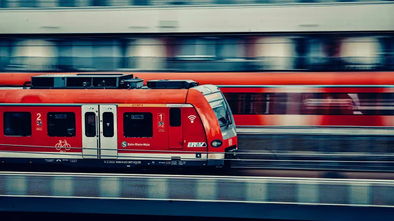 Two red trains running on side-by-side tracks. The larger outpaces the smaller one, symbolizing how AI moves faster than enterprise security.