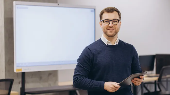Person standing in front of a smart board and holding an iPad