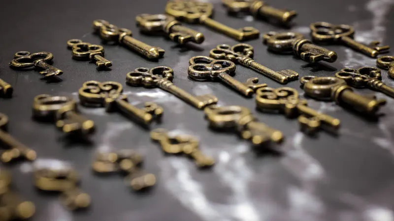 A series of old-fashioned brass keys on a shiny gray surface to symbolize Jamf Bring Your Own Key.