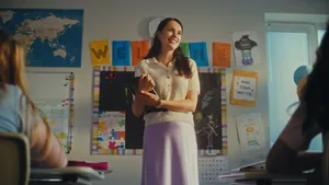 Smiling teacher in front of classroom holding an iPad