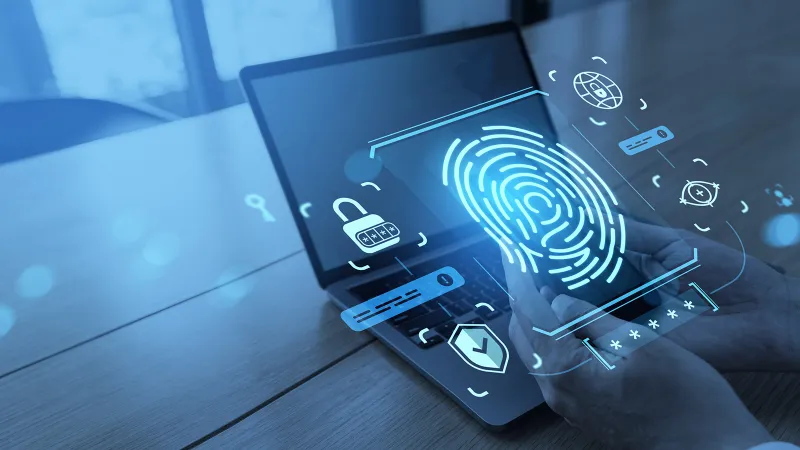 Stylized photograph of Jamf passkeys: hands are on the keyboard of a Mac Air. Floating above the hands and laptop are icons for fingerprints and other passkey types.