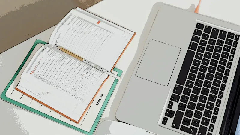 An illustration of an office calendar lying open next to a MacBook