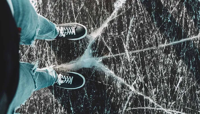 Person standing on frozen ice lake that is cracking beneath their feet