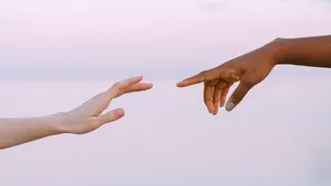 Two hands reaching out to touch fingertips.
