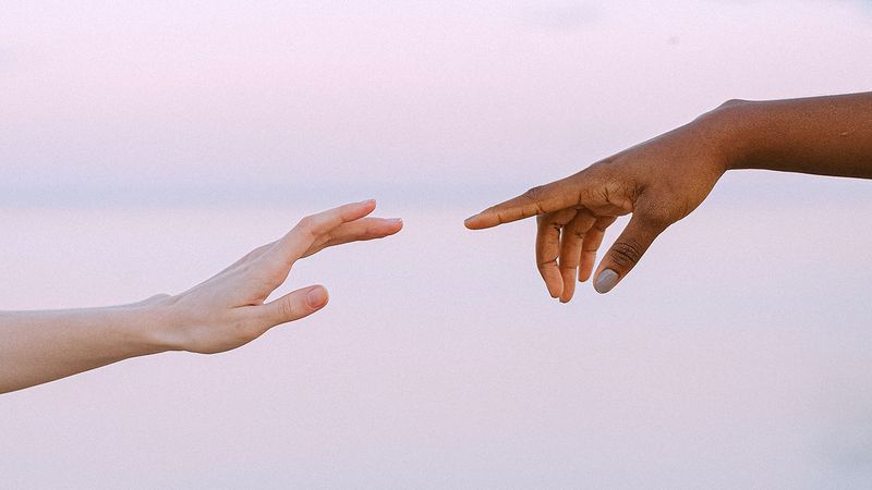 Two hands reaching out to touch fingertips.