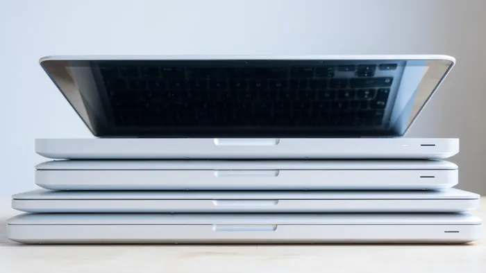 Stack of four Macbooks, with the top Macbook slightly open