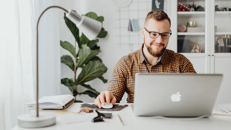 man sits typing at Apple computer laptop.