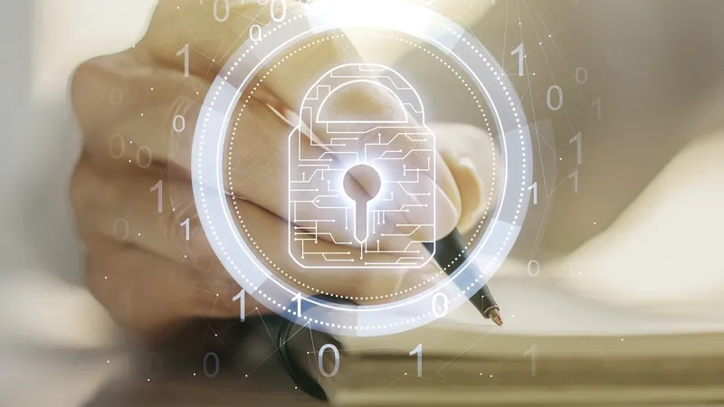 Hand taking notes by computer managed by Jamf is overlaid with security lock icon.