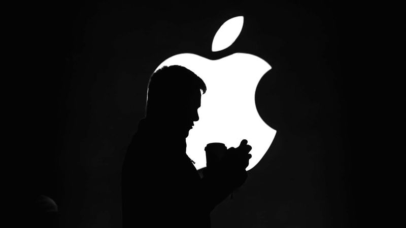 Silhouette of an iPhone user in front of the Apple logo