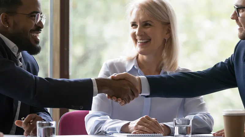 An employee shakes hands with someone on his first day onboarding to a new job.