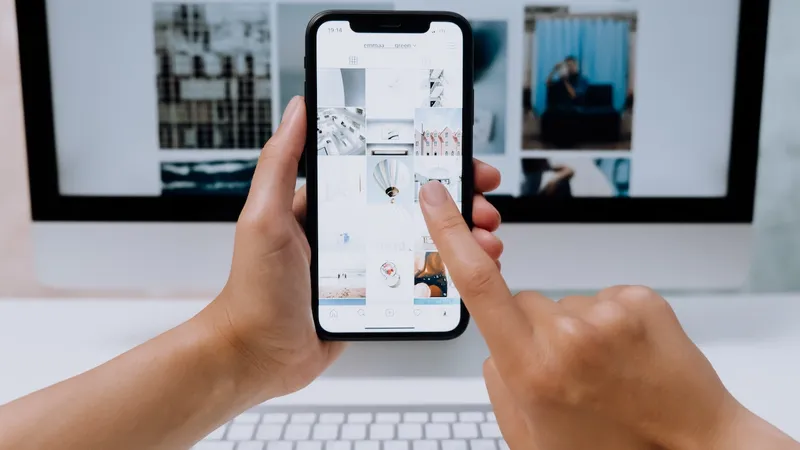 Hand holds iPhone in front of computer screen