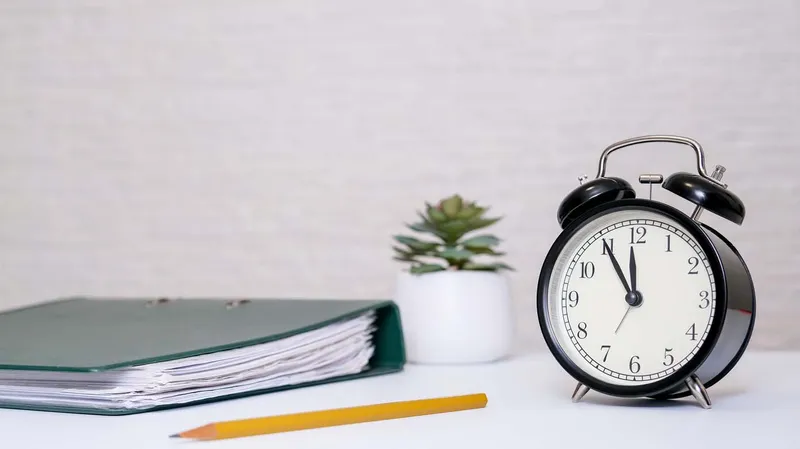 Notebook, pencil and alarm clock on a desk