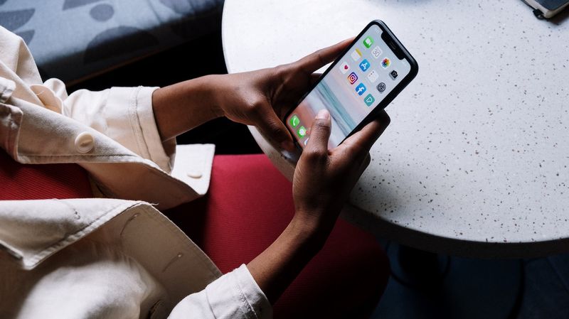 Holding iPhone showing apps on screen.