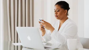 Worker sits at desk looking at iphone managed by Jamf.