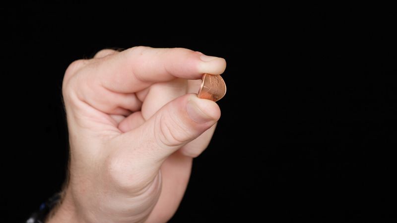 Hand squeezing a penny, causing it to bend