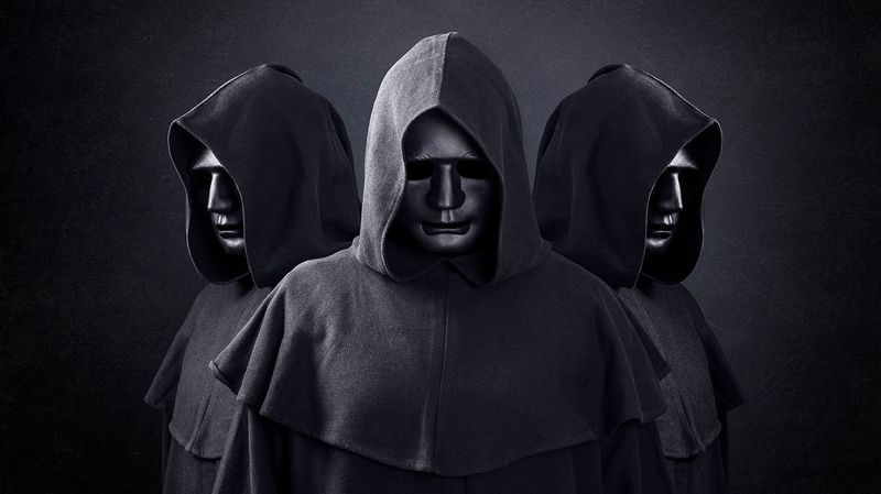 Three hooded figures wearing masks made of metal