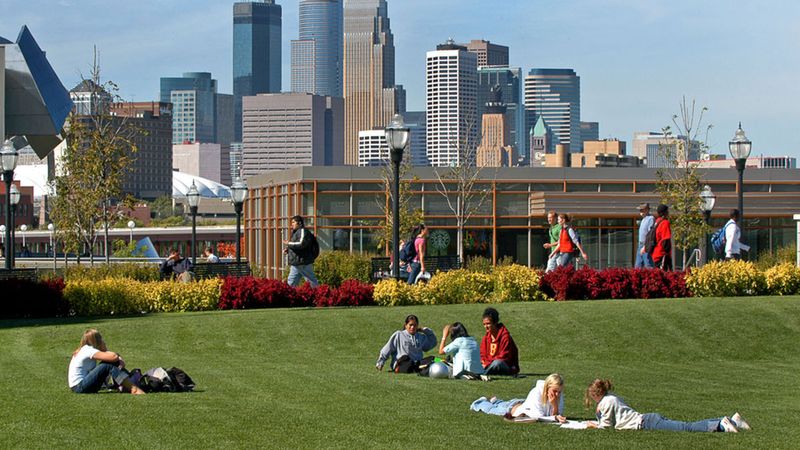 Students at the University of Minnesota lie on the grass and walk on paths.