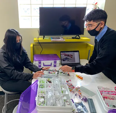 Two Chriso Ray students work together on circuits at a table loaded with computer components as they build and equip an Innovation Hub for inner-city students in Minneapolis, Minnesota, USA.