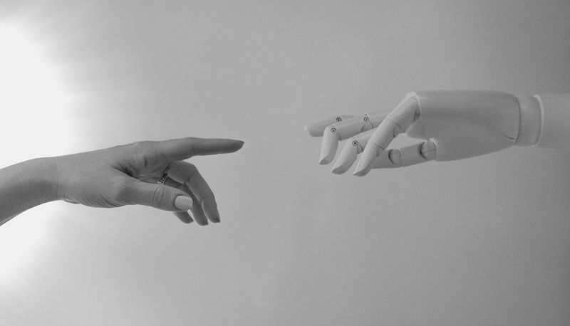 Human hand reaching out to touch robot hand.