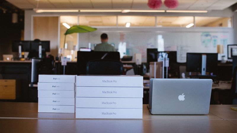 Stacks of new iPad and MacBook Pro boxes next to MacBook