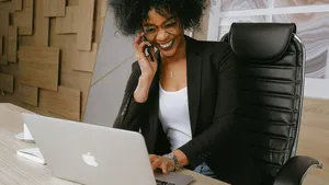 A businesswoman on the phone and working on a MacBook.